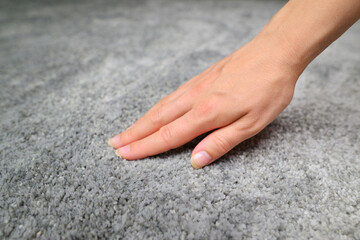 Close up of hand touching soft carpet. Gentle and fluffy carpet between fingers.
