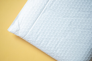 White padded envelope with bubble wrap on yellow background