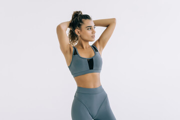 Obraz premium Smiling sports woman standing with arms folded and looking at camera on a white background