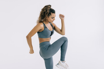 Portrait of a fit sportswoman doing leg exercises isolated over gray background