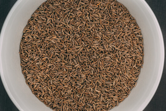 Closeup shot of dried cumin seeds in a white bowl