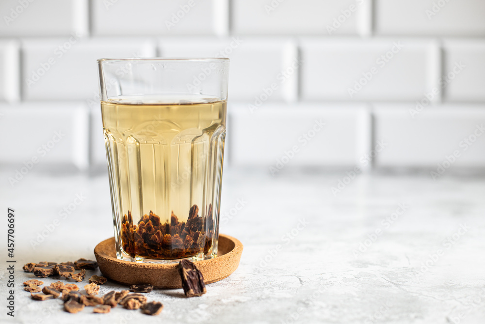 Wall mural carob tea in glass on light background with seeds