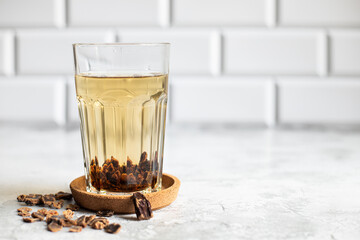 carob tea in glass on light background with seeds