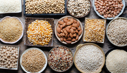 Top view of dry organic cereal and grain seeds in wooden and ceramic bowl on grunge wooden background in dark tone, for clean food ingredient or agricultural product concept