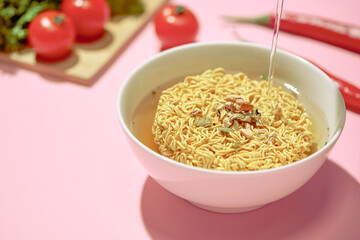 Pouring hot water into instant noodles in a bowl