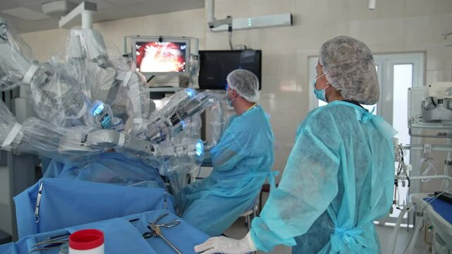 Microsurgery with robotic equipment. Surgeons observe the operation process on monitor of modern medical machine in hospital.