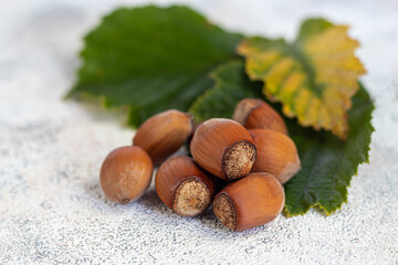 Hazelnuts on a light background with green leaves. Contains beneficial vitamins and minerals.