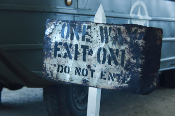 Old rusty metallic sign reading One Way Exit Only Do not enter