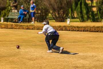 Green lawn bowling female player throwing ball