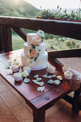 White wedding cake with flowers on a wooden table.