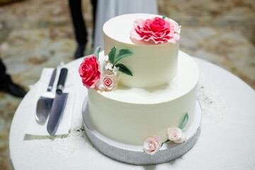 White wedding cake with flowers on a wooden table.