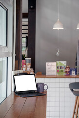 Blank white screen tablet with magic keyboard on wooden counter table in cafe room.