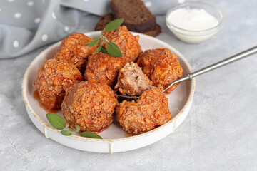 Meat balls on a light background with sage and parsley leaves. Homemade lunch.