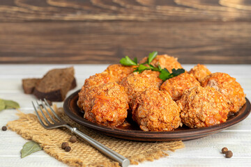 Meat balls on a light background with sage and parsley leaves. Homemade lunch.