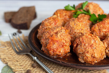 Meat balls on a light background with sage and parsley leaves. Homemade lunch.