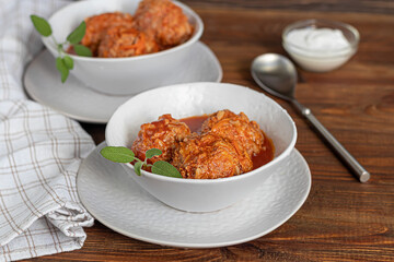 Meat balls on a wooden background with sage and parsley leaves. Homemade lunch.