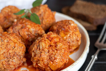 Meat balls on a wooden background with sage and parsley leaves. Homemade lunch.