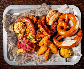 Oktoberfest beer menu germany traditional rustic style, veal pretzel, sausage with mustard in white plate on wooden rustic table.