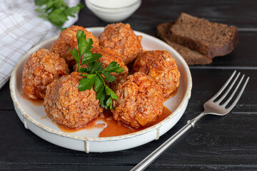 Meat balls on a wooden background with sage and parsley leaves. Homemade lunch.