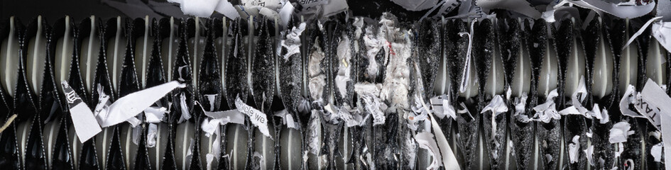 Close up view of home paper shredder teeth jammed with shredded paper