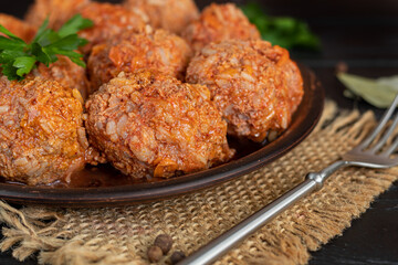 Meat balls on a wooden background with sage and parsley leaves. Homemade lunch.