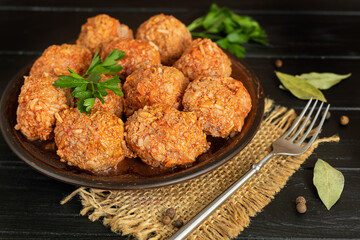 Meat balls on a wooden background with sage and parsley leaves. Homemade lunch.