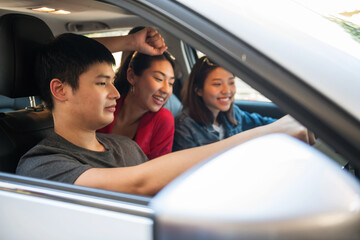 Happy Asian friends drive car for road trip