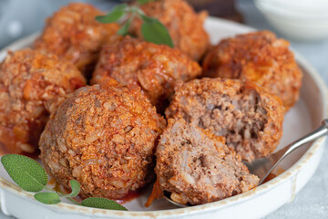 Meat balls on a light background with sage and parsley leaves. Homemade lunch.