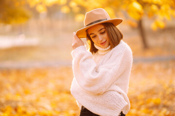 Sunny lifestyle portrait of young stylish woman walking on park, wearing cute trendy hat. Fashion, style concept. People, relaxation and vacations concept.