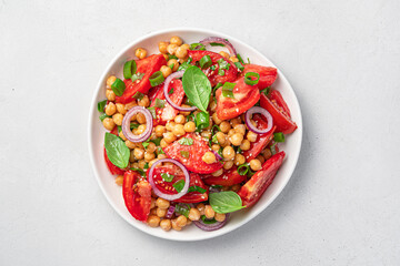 Fresh, healthy salad with tomatoes, chickpeas, basil and sesame on a gray background.