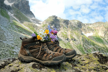 mountains and touristic hiking boots with flowers. mountains summer landscape. atmosphere travel natural background. world tourism day, journey concept