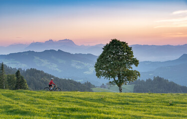 nice senior woman on electric mountain bike at sunset in the mountains of Bregenz Forest,...