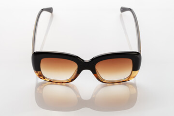 Sunglasses on a white reflective surface. Fashionable, stylish accessories.  Use it for a vacation or summer concept.