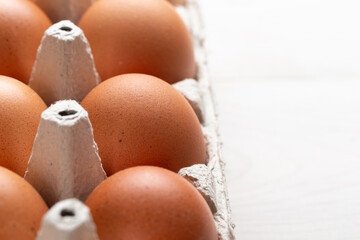 Fresh organic chicken eggs in carton pack or egg container  on white wood background.