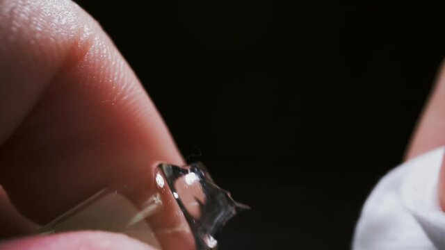 CU, macro: scientist breaks glass ampule with experimental antiviral vaccine holding cotton pad disk on black background in lab extreme close view