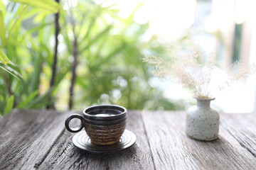 Coffee in a cup made of palm tree with dry grass flower in white vase