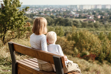 Mother and son sitting on a bench and looking at the city landscape