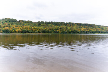 View of the river and the hill covered with forest in autumn