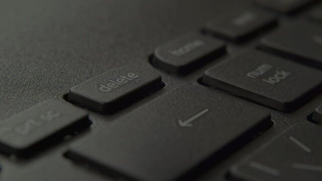 The finger presses the backspace button on the keyboard