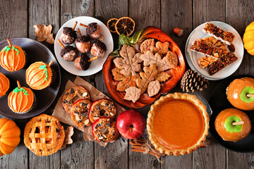 Autumn desserts table scene with a variety of sweet fall treats. Above view over a dark wood...