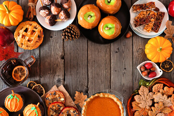 Autumn desserts frame. Table scene with a variety of sweet fall treats. Overhead view over a dark wood background. Copy space.