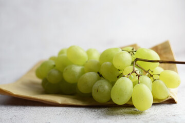 Bunch of grapes in a small kraft paper bag. Stone background, copy space.