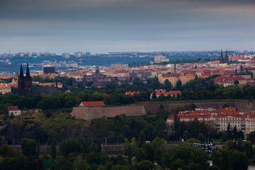 Fototapeta na wymiar Une vue de Vysehrad à Prague. Une vue de Vysehrad avec ses fortifications et sa basilique. Derrière se trouve le centre-ville de Prague, les églises dépassent des toits.