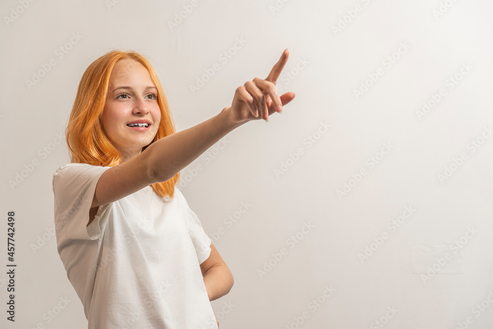 Wall mural Portrait of a teenage girl with red hair and a white T-shirt showing up on a light background