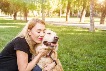 Young blond woman hugs her dog.