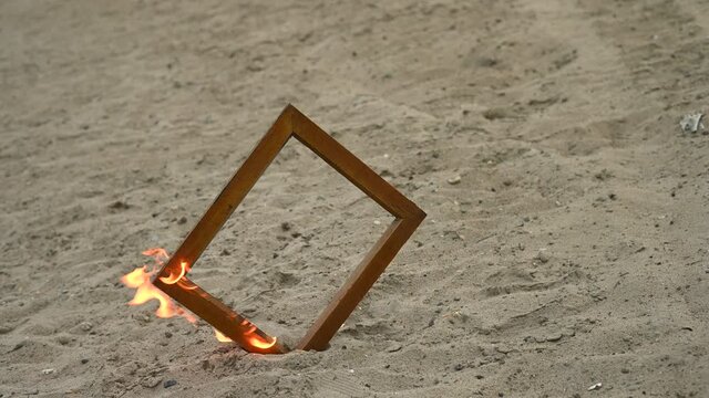 Wooden photo frame on fire on the beach.