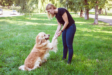 Young blond woman holding a dog by the front paws.
