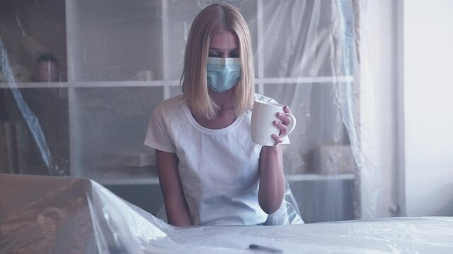 Office quarantine. Lockdown isolation. Covid unemployment. Business shutdown. Stressed woman in protective face mask suffering from pandemic restrictions at workplace interior.