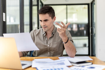 A businessman holding a sales document that the sales department summarizes, he looks displeased when he sees reports of falling sales, he shows signs of stress. Failed sales management concept.