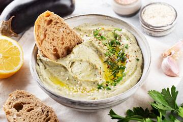 Baba ghanoush, babaganoush or eggplant hummus on the bowl with bread and all ingredients, close up